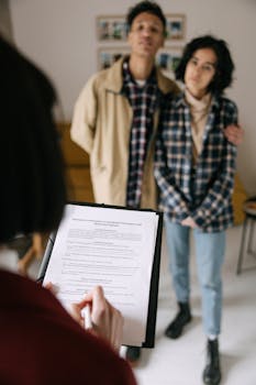 A focused view of a couple discussing a real estate document with an agent in an apartment setting.